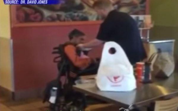 Joven empleado de una cadena de comida rápida le da de comer a una mujer discapacitada