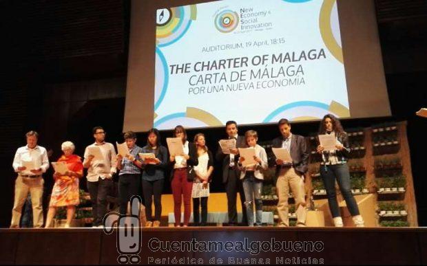 Niños y adultos leen en grupo la "Carta de Málaga", documento de referencia de la Nueva Economía.