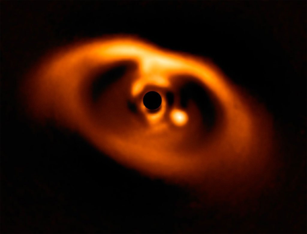 Primera imagen de la formación del planeta PDS 70b, visible como un punto brillante a la derecha del centro de la imagen y que queda oscurecido por la máscara del coronógrafo, que bloquea la intensa luz de la estrella central. / ESO/A. Müller et al.